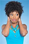 Happy African American woman covering ears over while looking away colored background