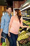 Heureux jeune couple regardant les uns les autres lors de vos achats de légumes au marché