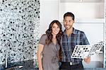 Beautiful happy couple with color samples in modern kitchen