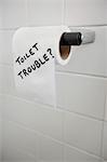 Close-up of text written on tissue paper in bathroom depicting toilet problems