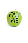 Close-up of text on a granny smith apple reading eat me over white background