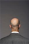 Bald headed businessman with barcode on his neck over gray background