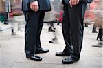 Two Businessmen Standing Amongst Pedestrian Traffic