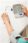 Senior woman using an automatic blood pressure cuff  to monitor her health at home.