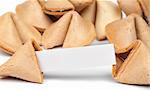 A fortune cookie with fortune paper in front of a pile of other cookies isolated on white.