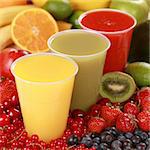 Cups with different kinds of juices surrounded by fresh fruits