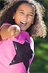 Portrait of a beautiful young happy mixed race interracial African American girl pointing, shot outside in summer sunshine