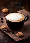 cup of cafe au lait and biscotti on dark wooden background