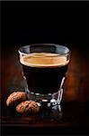 glass of espresso and biscotti on dark wooden background