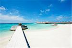 Row of water villas in the Maldives and a jetty with deck chairs