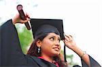 Young Asian Indian female student adjusting her graduate hat