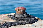 Old rusty mooring bollard on pier by the sea