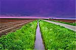 Asphalt Road along Canal and Protective Dam  in the Netherlands, Sunset