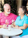Senior couple enjoying a glass of wine and conversation at an outdoor cafe.
