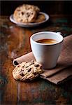 cup of espresso coffee and chocolate chip cookies on dark wooden table