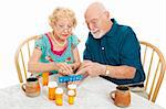 Senior couple at the table, sorting their medications for the week.  White background.