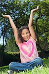 Portrait photograph of a beautiful young smiling happy mixed race interracial African American girl, shot outside in a park with her arms in the air