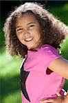 Portrait photograph of a beautiful young smiling happy mixed race interracial African American girl, shot outside in a park in summer sunshine