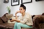 Jeune femme assise sur le sofa avec smartphone