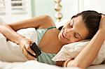 Young woman in bed with smartphone