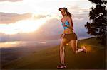 Young woman running in rural setting at sunrise