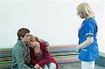 Young couple with nurse in hospital waiting room