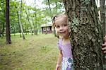 Mädchen versteckt sich hinter einem Baum