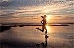 Woman running on beach at sunrise