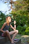 Girl sitting on steps and blowing bubbles