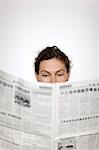 Close up of womans head behind newspaper