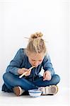 Portrait de jeune fille mange avec des baguettes