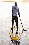 Man rowing paddle board in water, rear view