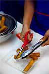 Person cutting deep fried spring rolls, close-up