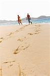 Diving flipper prints on sand, mid adult couple in background