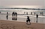 Puri beach on the Bay of Bengal, Indian families relaxing and paddling, beach vendor walking by in the late afternoon, Puri, Orissa, India, Asia