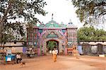 Ascetics walking through ornately carved and painted entrance to Joranda monastery complex, Joranda, Orissa, India, Asia