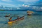 Jeunes garçons pêcher dans le lagon de Marovo sous les nuages dramatiques, îles Salomon, Pacifique