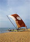 Fisherman and Oruvas (traditional outrigger dug-out canoe), Negombo beach, Western Province, Sri Lanka, Asia