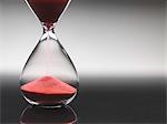 Pink sand pouring through hourglass