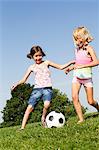 Girls playing soccer in field