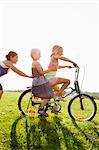 Girls playing with bicycle in grass