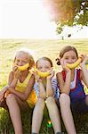 Mädchen halten Bananen über Mund