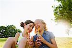 Laughing girls drinking juice outdoors