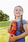 Jeune fille souriante transportant des pommes à l'extérieur