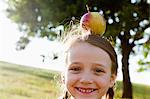 Smiling girl balancing apple on head