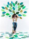 Girl using cell phone by tree on wall