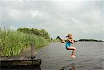 Girl jumping into rural lake