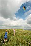 Mother and daughter flying kite in field