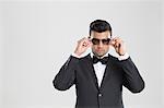 Man in tuxedo adjusting his sunglasses