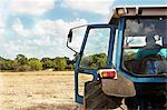 Farmer sitting in tractor in crop field